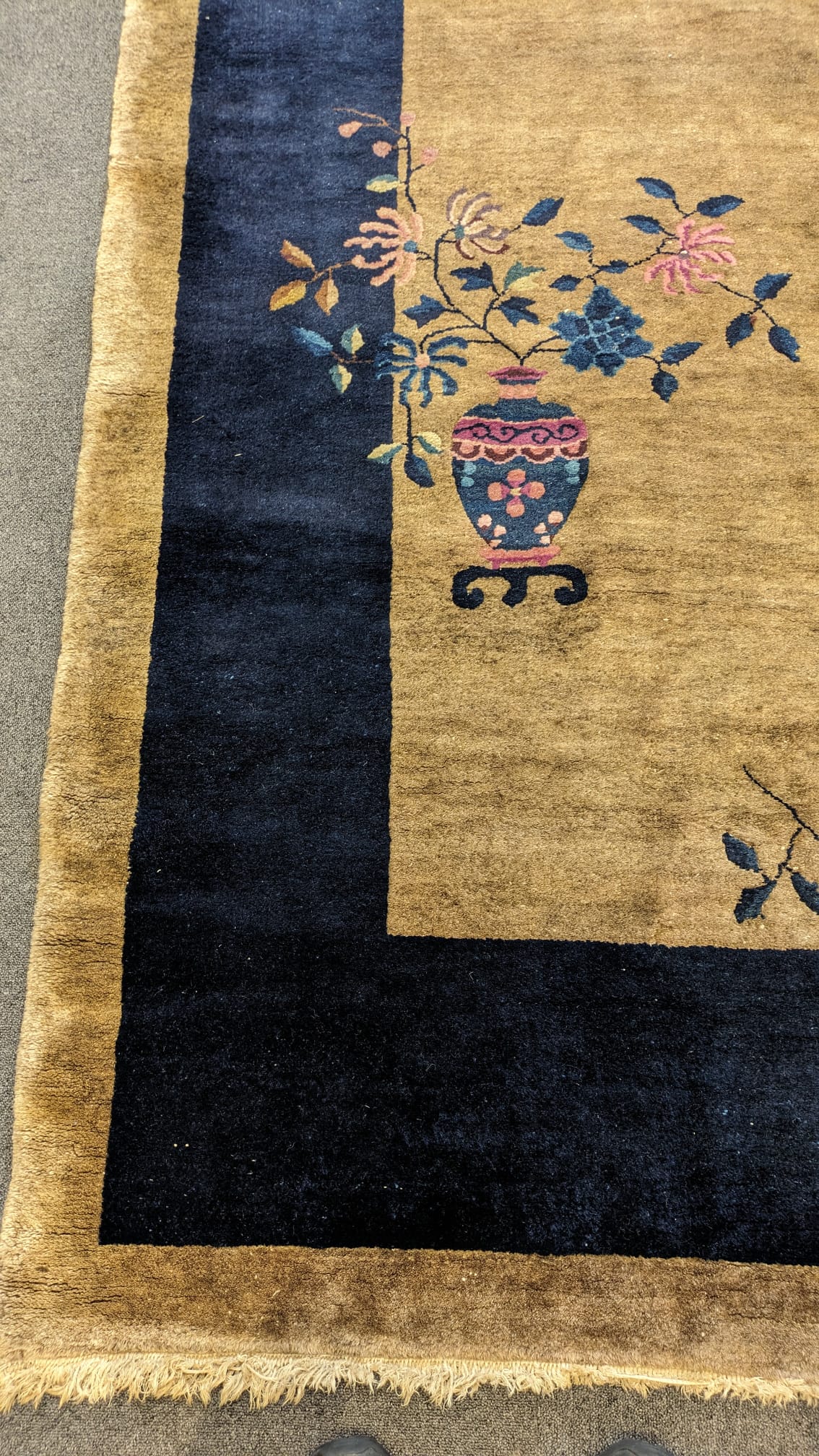 A Walter Nichols Chinese champagne ground carpet with asymmetrical decoration of flowers and an urn, single dark blue border, 350 x 280cm. Condition - fair
